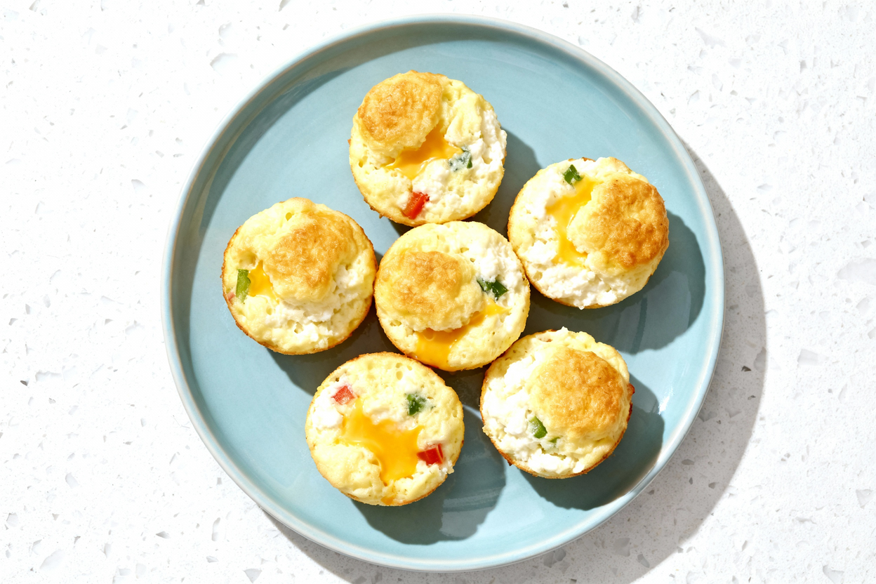 down view of fluffy cottage cheese egg bites arranged on a light blue ceramic plate, placed on a whi