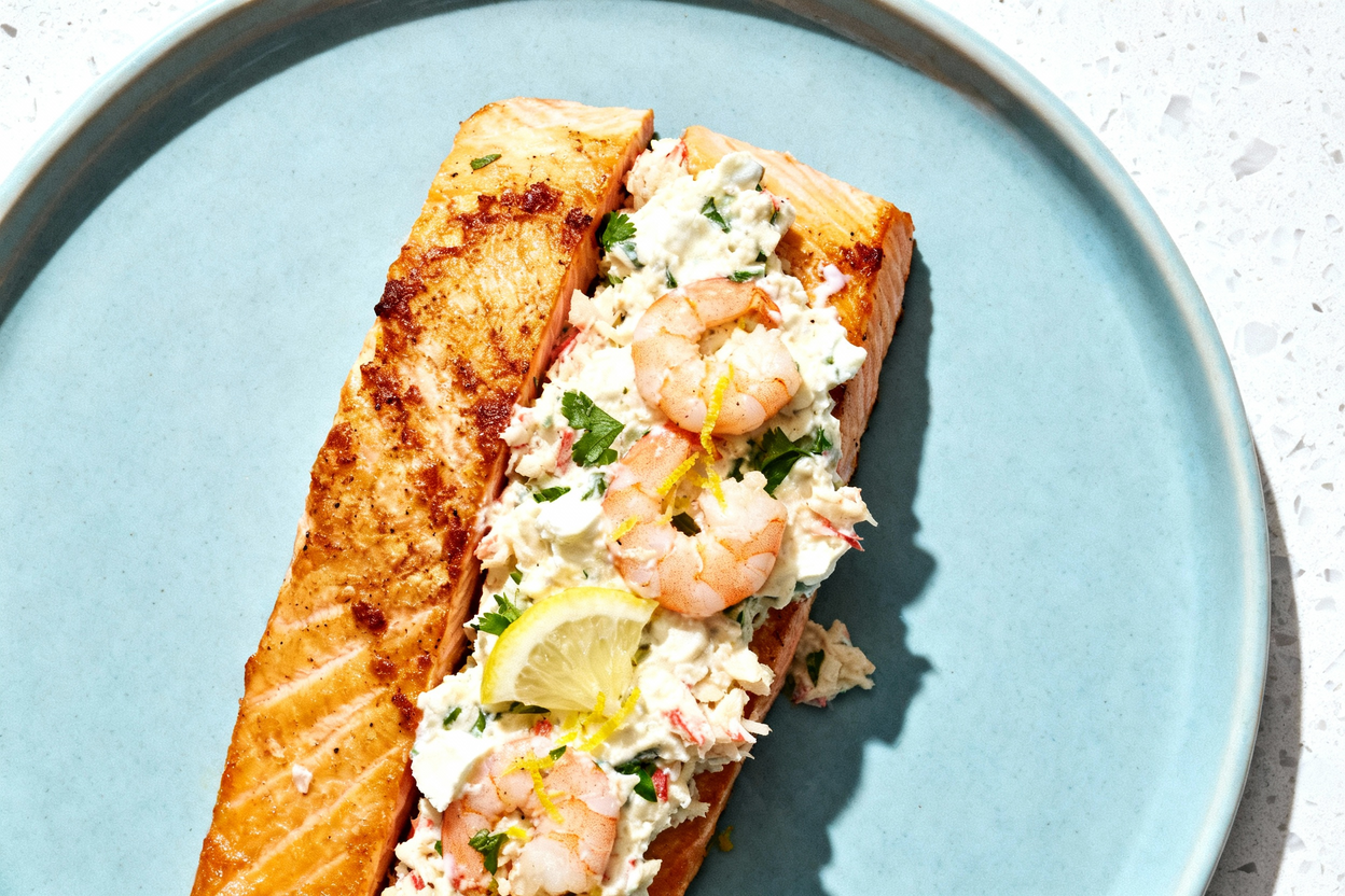 d, top-down photo of a single serving of keto crab and shrimp stuffed salmon, plated on a light blue