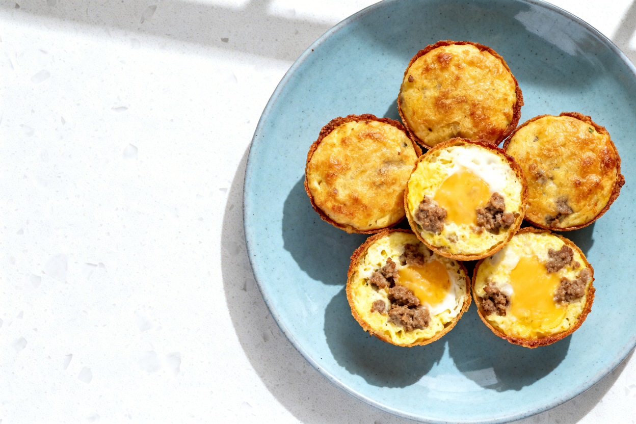 top-down food photo of a single serving of keto grab-and-go sausage egg muffin bites on a light blue