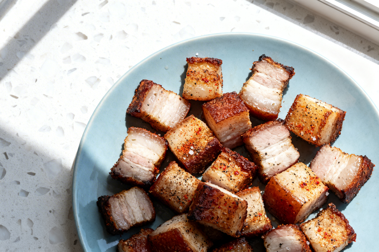 top-down food photo of keto pork belly bites: evenly cut cubes of roasted pork belly with deeply bro