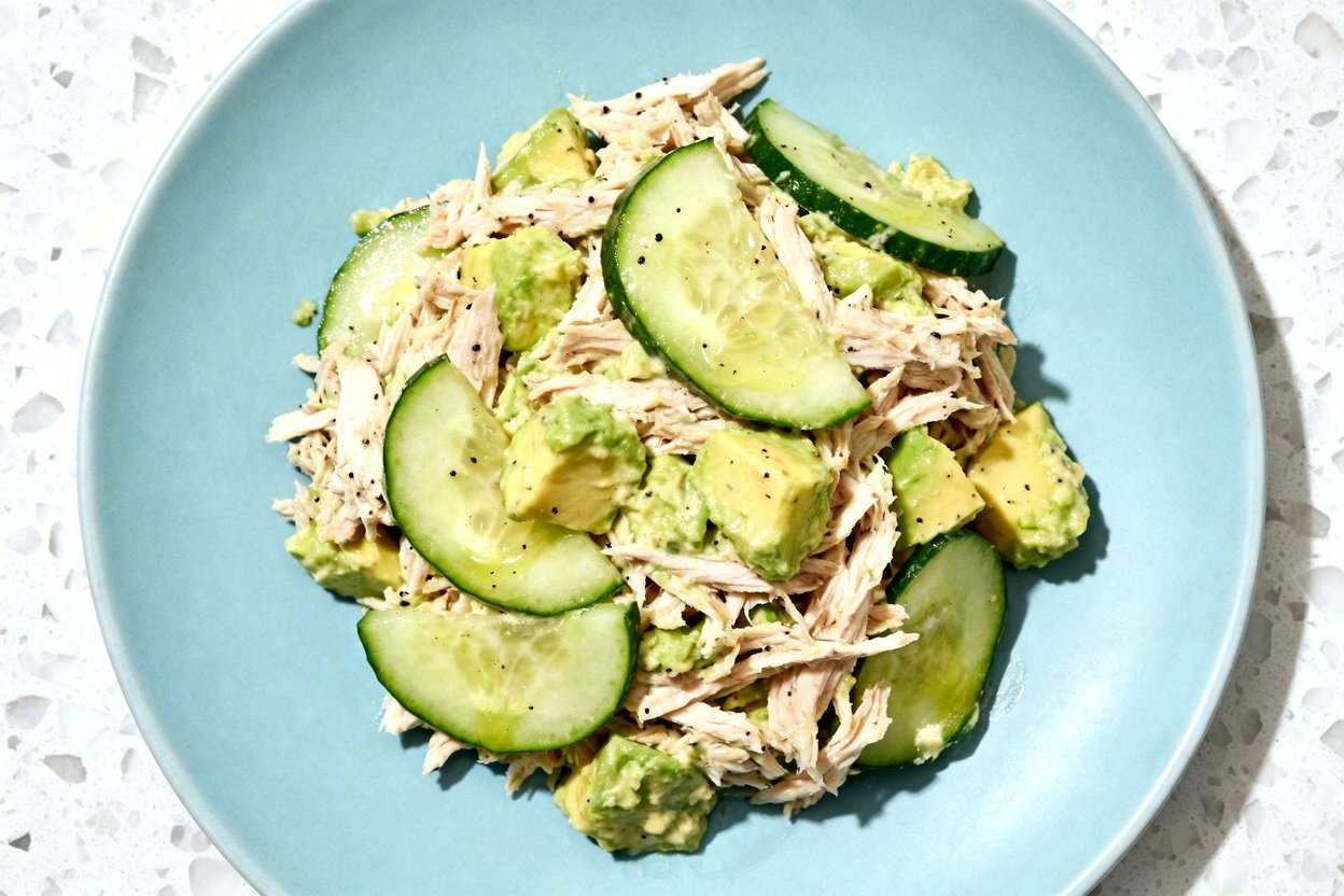 top-down food photograph of a finished keto avocado chicken cucumber salad: a casual, non-symmetrica