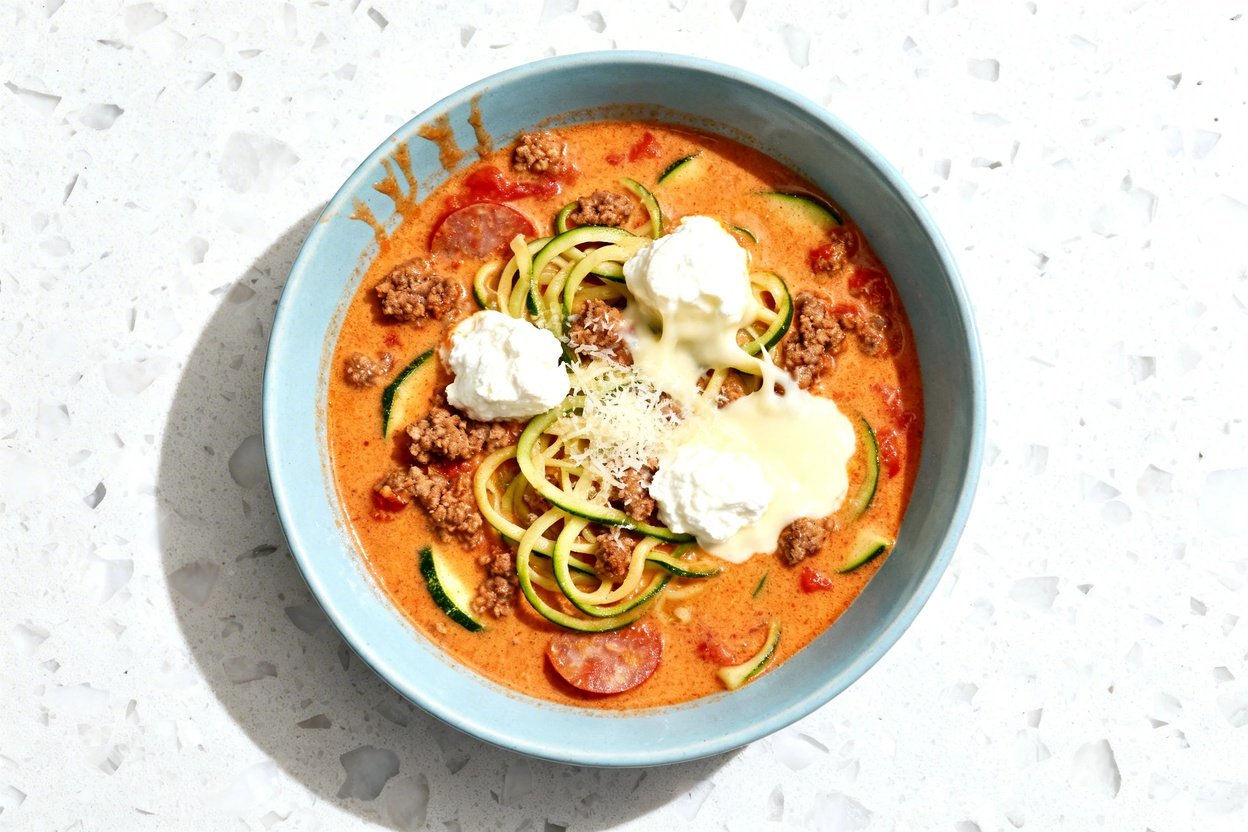 top-down food photo of a single serving of cheesy keto lasagna soup centered in a light blue ceramic