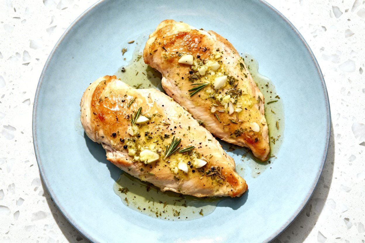 top-down food photo of keto baked garlic herb chicken: one light blue ceramic dinner plate holding a