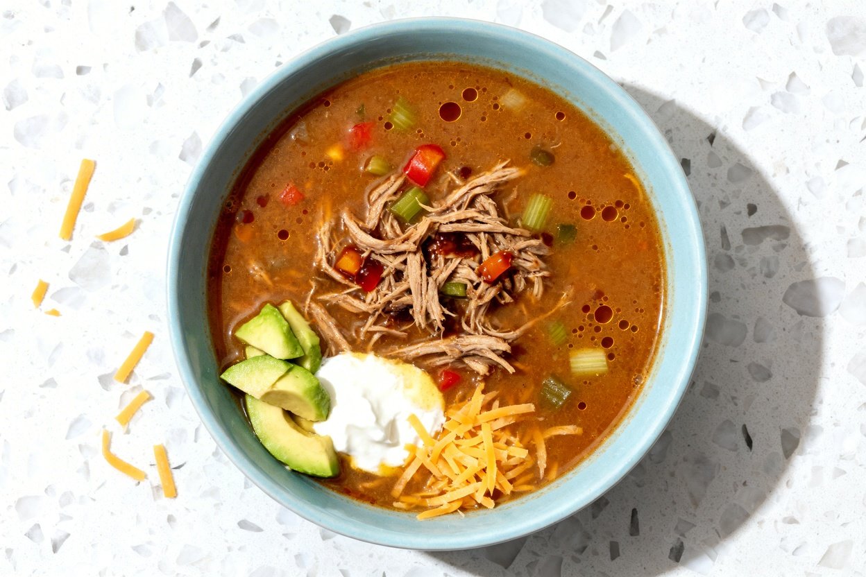top-down food photo of a single serving of Keto BBQ Pulled Pork Soup centered in a light blue ceram