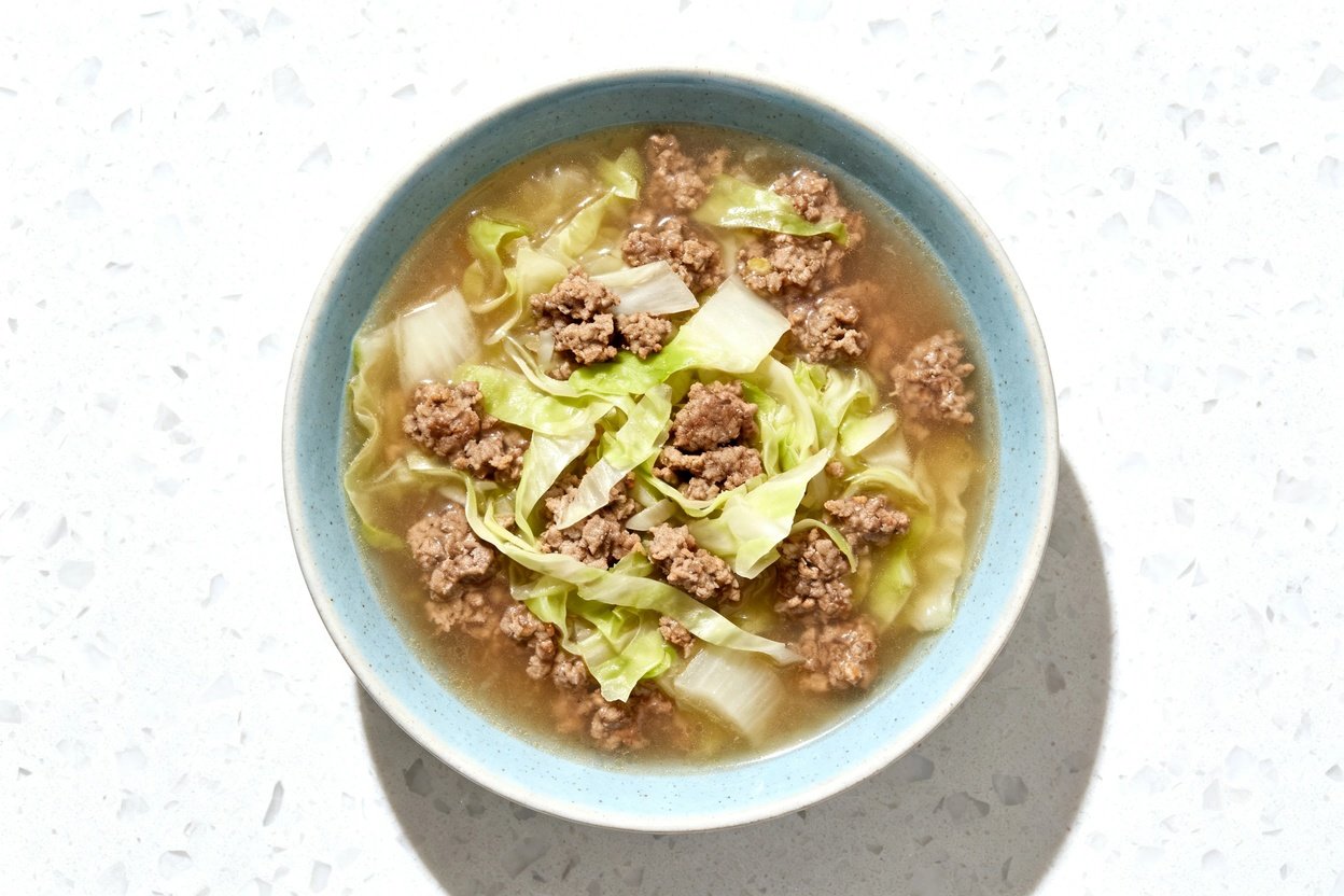 top-down food photo of a single serving bowl of finished keto beef and cabbage soup: a hearty, broth