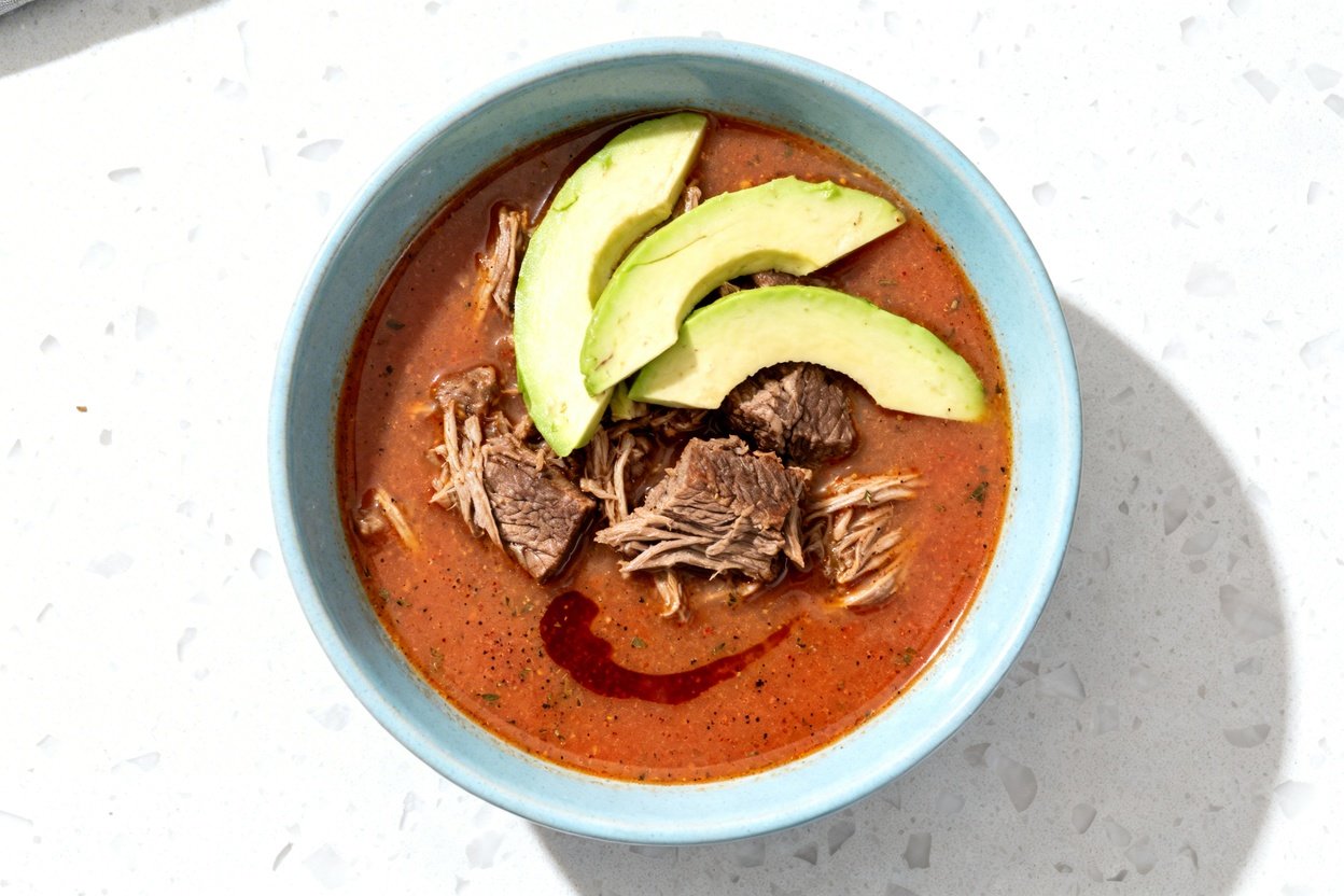 top-down food photo of a single serving bowl of keto Mexican beef soup: tender shredded beef chuck c