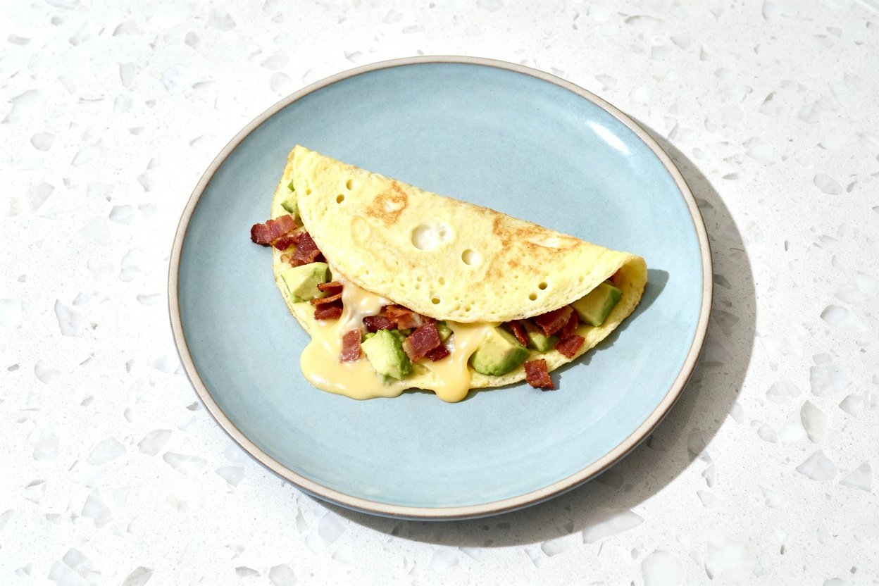 top-down food photo of a single serving low carb avocado bacon omelette (classic folded omelette met