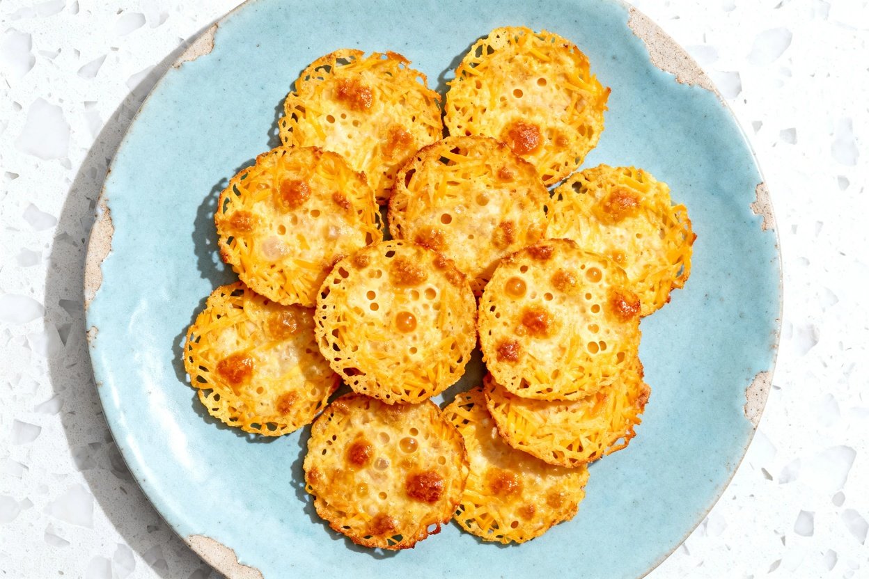 top-down food photo of a single serving of keto cheese crisps: 10–12 small, round, lacy-edged baked