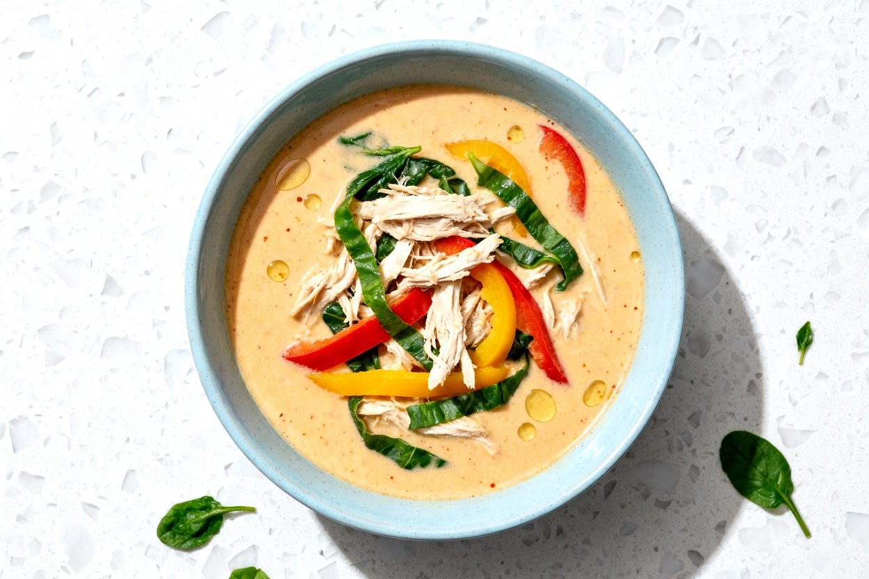 top-down food photo of a single serving of Keto Coconut Curry Chicken Soup: a creamy, pale golden-or