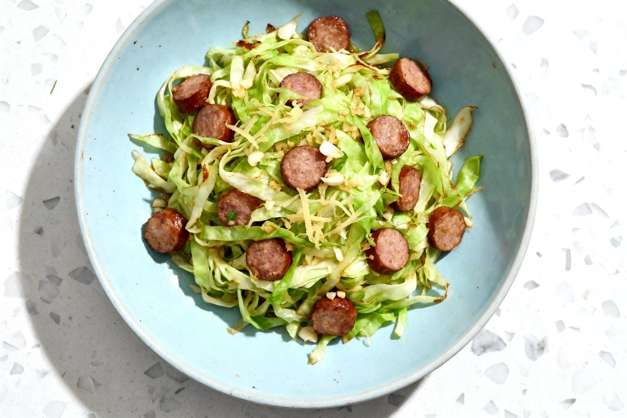 top-down food photograph of a single serving of keto cabbage stir fry with sausage: thinly sliced gr