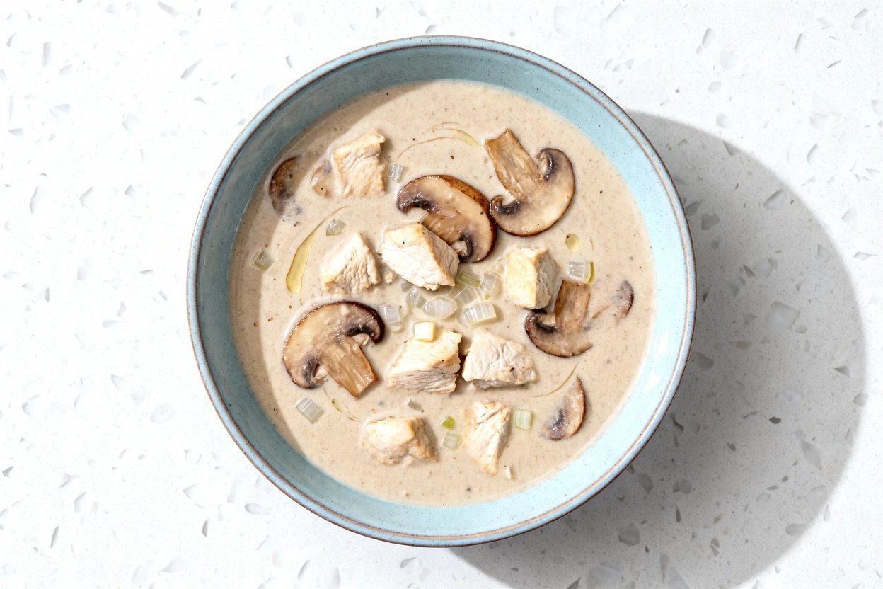 top-down food photo of a single serving of keto creamy chicken mushroom soup: a thick, rich, velvety
