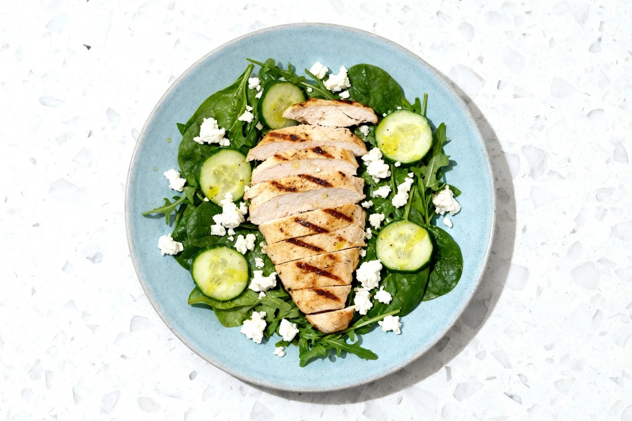 top-down food photo of a finished keto grilled chicken feta salad, single serving centered on an id
